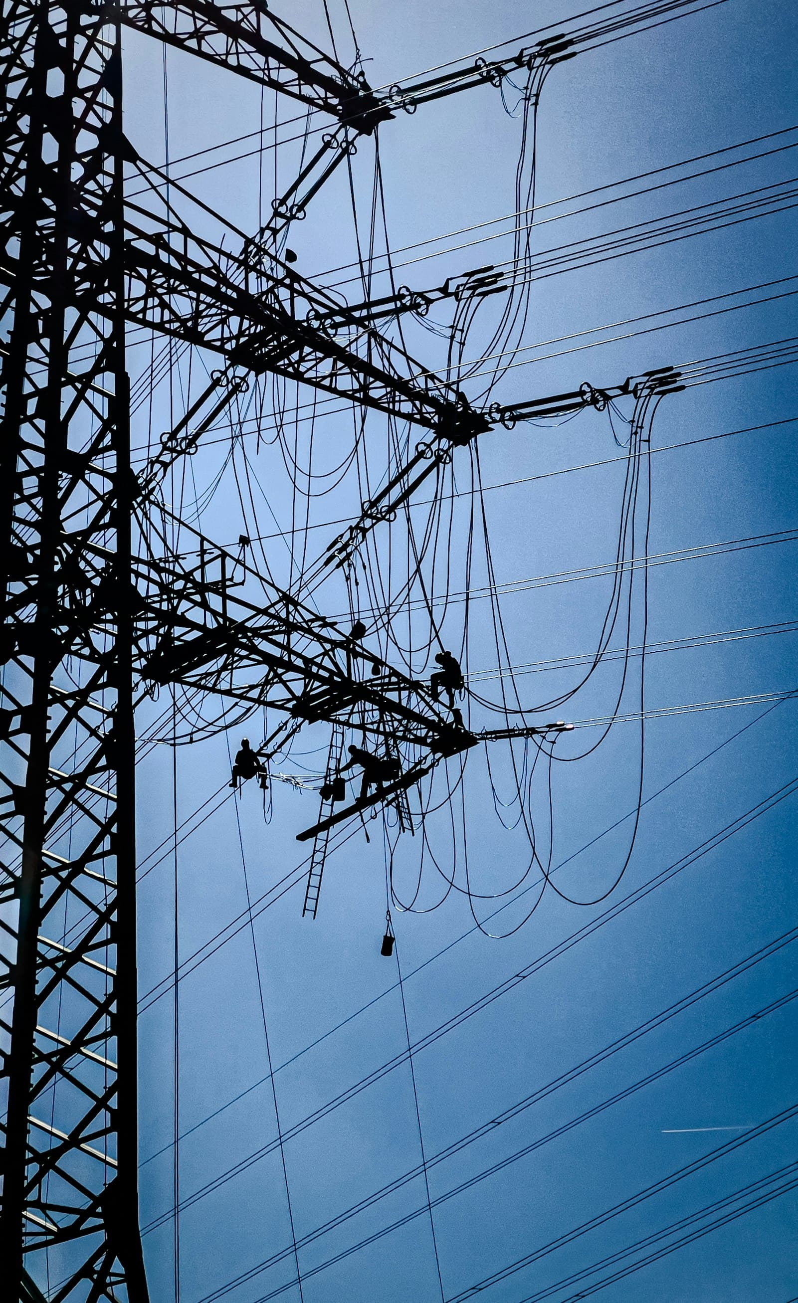 Linemen working at height on a high-voltage transmission tower